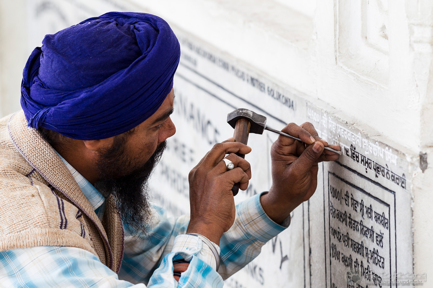 Indischer Handwerker meiselt eine Inschrift in die Marmorplatte