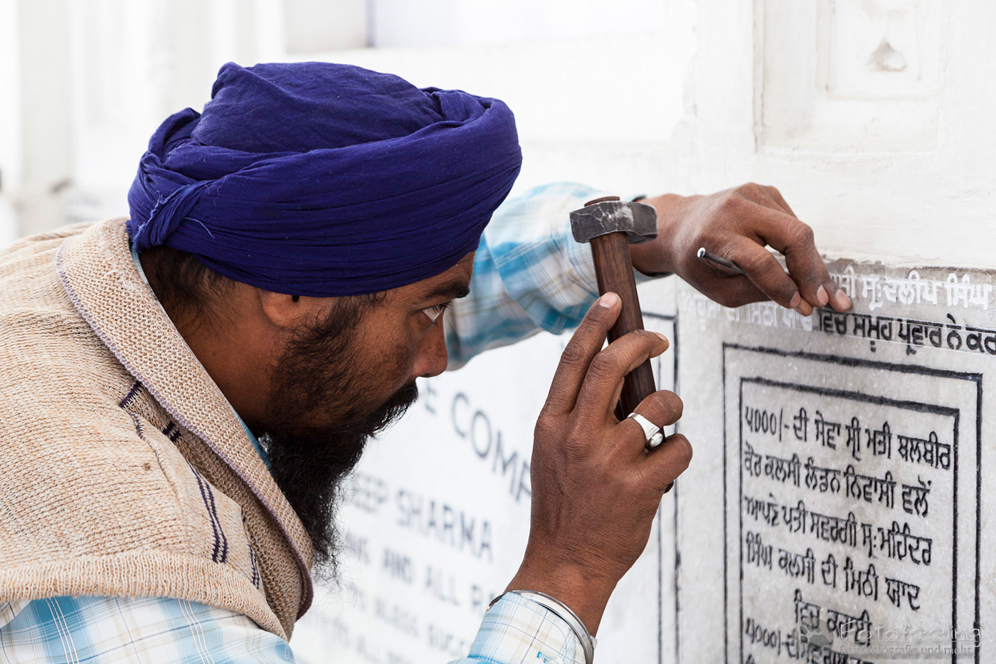 Indischer Handwerker meiselt eine Inschrift in die Marmorplatte