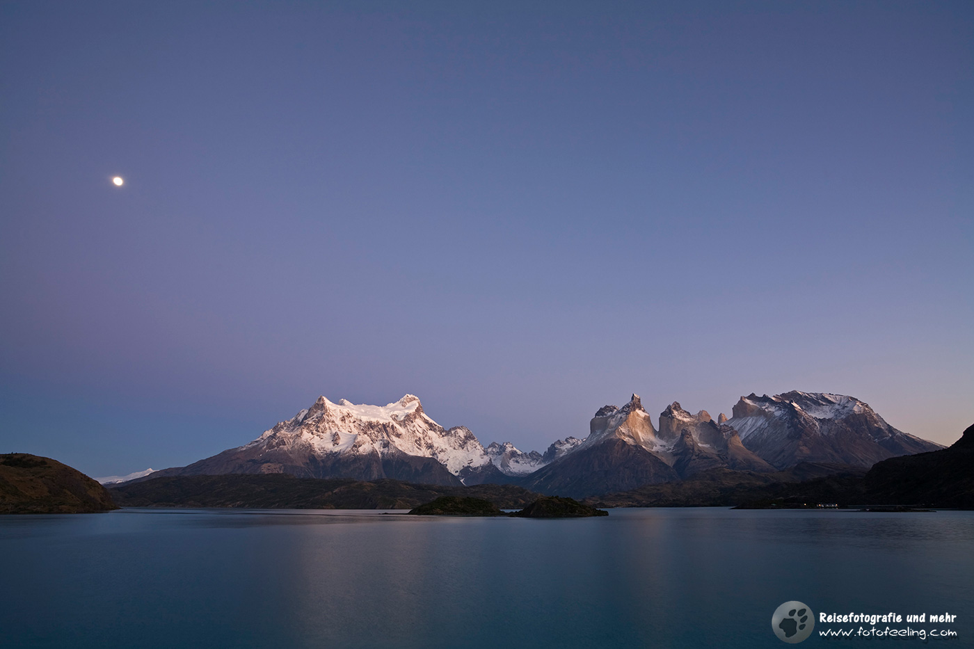 Der Mond bescheint das Torres del Paine Bergmassiv am See Lago Pehoe kurzvor Sonnenaufgang